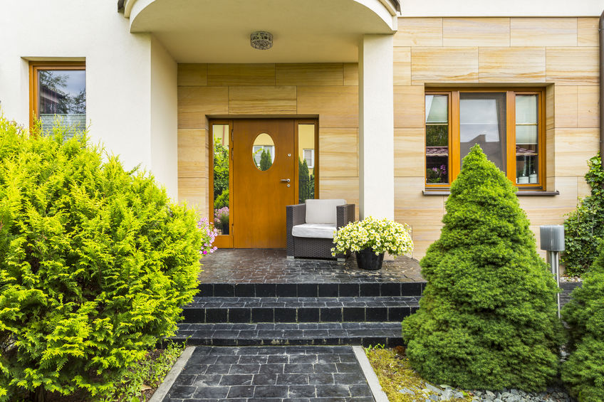 Stylish front entrance to the modern family house with spruces next to cobblestoned pathway